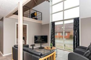 a living room with a couch and a tv at Stort Aktivitets-Feriehus Med Fri Badeland, Bowling, Badminton Og Tennis, in Henne