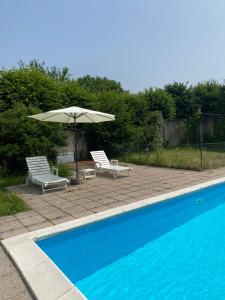 a swimming pool with two chairs and an umbrella at Il Dondolo di Villa Carlotta Mozzo in Mozzo