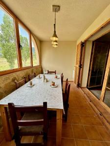 Un comedor con mesa y sillas y ventanas. en Bungalow Esqui Valdelinares REF 066, en La Virgen de la Vega