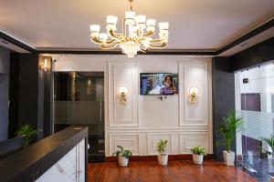 a lobby with a chandelier and potted plants at Hotel Adarsh in Khagaul