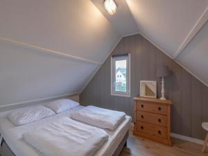 a bedroom with a white bed and a wooden dresser at Family Home near Dunes and Beach in Sint Maartensvlotbrug