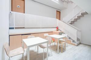 a kitchen with white tables and chairs and stairs at Hotel O Pondok Indah Near Gandaria City Formerly Odori Residence in Jakarta +18 photos