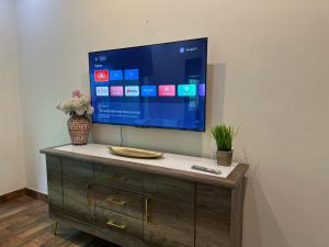 a flat screen tv on a wall with a wooden cabinet at Comfortable luxury Bedroom in Faisalabad