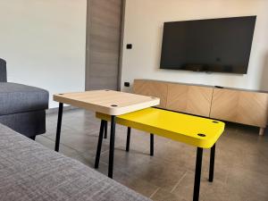 a yellow table and bench in a room with a tv at La Gare Apartments - Zerbion in Châtillon