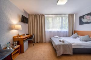 a hotel room with two beds and a desk and a window at Hotel Gromada Poznań Stadion in Poznań