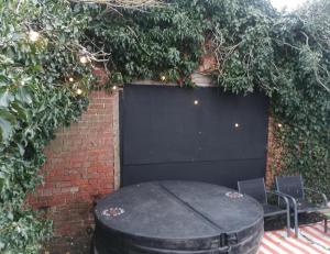 un barile nero appoggiato davanti a un muro di mattoni di Secret Heated Dome, Hot Tub,Firepit Projector in Lincoln a Lincoln