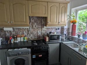 a kitchen with a stove and a microwave at Oakley Court Room in Wallington