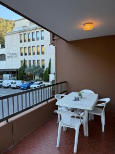 einen Balkon mit einem weißen Tisch und Stühlen sowie einer Straße in der Unterkunft Studio tout équipé face aux thermes in Amélie-les-Bains-Palalda