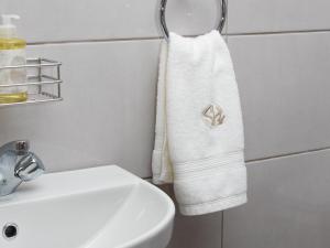 a white towel hanging on a wall next to a sink at Sage Haven Guesthouse in Modimolle +25 photos