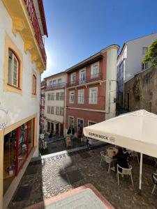 a patio with a white umbrella and tables and buildings at Casinha PP Guest House in Coimbra