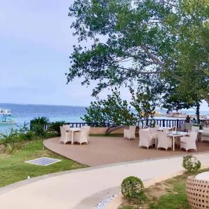 a group of tables and chairs next to the ocean at One Pacific Residence with Ocean View in Mactan