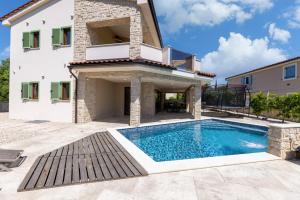 a villa with a swimming pool in front of a house at Villa Divina in Milohnići