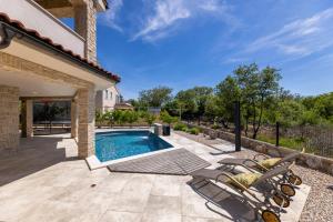 a patio with a swimming pool and chairs next to a house at Villa Divina in Milohnići