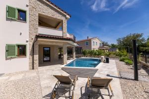 a backyard with a pool and chairs and a house at Villa Divina in Milohnići