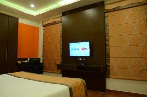 a bedroom with a bed and a tv on a wall at Hotel Ramaya in Gwalior