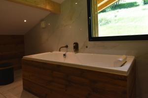 a large bath tub in a bathroom with a window at VAUJANYLOCATIONS - Chalet Sagha in Vaujany +21 photos