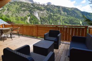 a deck with chairs and a table with a view of a mountain at VAUJANYLOCATIONS - Chalet Sagha in Vaujany