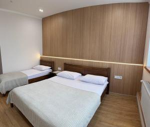 two beds in a room with wood paneling at Passage Hotel in Ternopilʼ