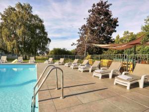 Una fila de tumbonas junto a una piscina. en Novotel Roissy Saint Witz, en Saint-Witz