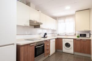 eine Küche mit weißen Schränken und einer Waschmaschine und einem Trockner in der Unterkunft Burriana Beach Retreat: Pool & Comfort in Burriana