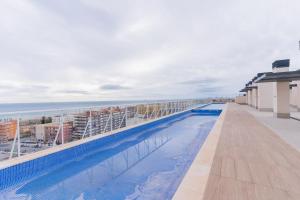 a swimming pool on the roof of a building with the ocean at Canet Seaview Gem: Pool & Beach Proximity in Canet de Berenguer