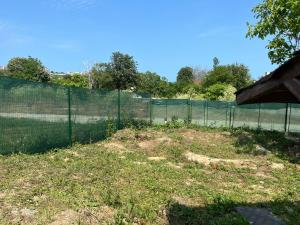 a tennis court with a fence in the grass at The Byala Escape, Private Villa with Bar & Hot Tub in Byala