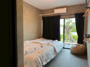 ein Bett in einem Schlafzimmer mit einem großen Fenster in der Unterkunft Phuwara poolvilla ภูวรา พูลวิลล่า in Hat Yai + 11 Fotos