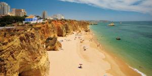 a group of people on a beach near a cliff at Atlantico Apartments in Portimão