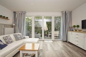 un soggiorno con un divano e un tavolo di Residenz Waldidyll FeWo Kleiner Stubber - ruhige Lage, mit Sauna- und Schwimmbadnutzung im AHOI Sellin a Ostseebad Sellin