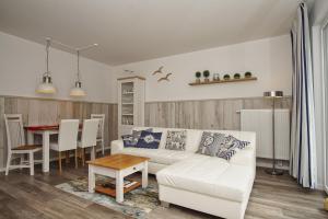 un soggiorno con un divano bianco e un tavolo di Residenz Waldidyll FeWo Kleiner Stubber - ruhige Lage, mit Sauna- und Schwimmbadnutzung im AHOI Sellin a Ostseebad Sellin