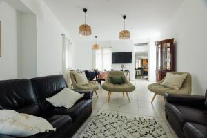 een woonkamer met een zwarte leren bank en stoelen bij Maison avec jacuzzi in Villeurbanne