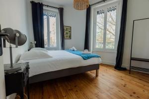 a bedroom with a large bed and two windows at Maison Yasmyn in Villeurbanne