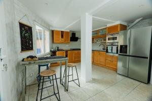 a kitchen with a stainless steel refrigerator and two bar stools at Maison Yasmyn in Villeurbanne