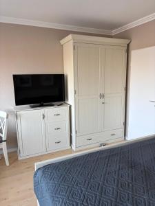 a bedroom with a tv and a white cabinet at Seeblick in Fehmarn