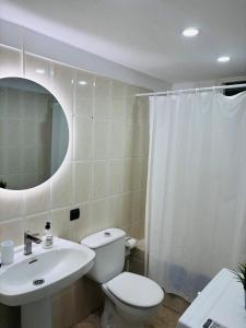 une salle de bain avec toilettes, lavabo et miroir dans l'établissement Apartamento con Vistas al Mar, à Los Cristianos