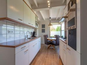 a kitchen with white cabinets and a dining table at Holiday Home Sint Maartenszee near Beach in Sint Maartensvlotbrug