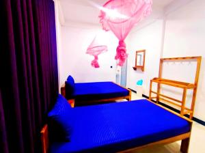 two beds in a room with blue sheets at Hilton Cottage in Trincomalee