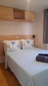 a bedroom with a white bed with blue and white pillows at Mobil- home Ohana Mar Estang in Canet-en-Roussillon