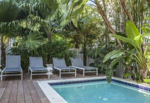 Una piscina con cuatro sillas al lado de una valla. en Windsor Townhomes 4, en Key West 16 fotos más