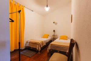 2 Betten in einem kleinen Zimmer mit gelben Vorhängen in der Unterkunft Apartamento 2 - Fundação de Veiros in Veiros