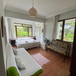 a bedroom with a bed and a couch and windows at Günebakan Taliani Otel in Ayvalık