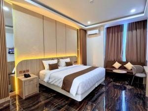 Una habitación de hotel con una cama grande y un sofá. en Fahira Hotel Syariah Padang, en Padang