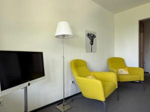a living room with two yellow chairs and a flat screen tv at FX Mayr Zentrum Bodensee in Überlingen
