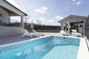 a swimming pool with white chairs and a house at Haus Šimuni in Kršan