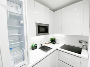 biała kuchnia ze zlewem i lodówką w obiekcie CARDANO SUITE - 5 min from Central Station w Mediolanie