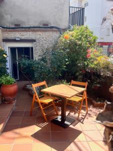 een houten tafel en 2 stoelen op een patio bij Apartamento Nuria,Centro del Pueblo,Planta baja con jardin, Aire Acondicionado in L'Escala