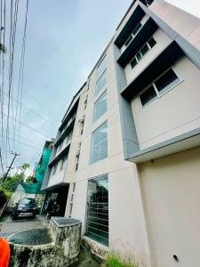 a white building with a car parked in front of it at Crystal inn BY D2V in Kakkanad