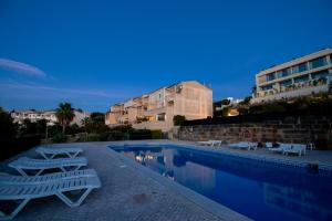 a swimming pool with two lounge chairs and a building at Apartment Bela Vista in Estômbar