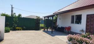 a white house with a fence and red chairs at Casa Geo in Vadu
