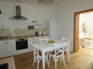 Una cocina blanca con una mesa y sillas blancas. en Bara ház, en Tvrdošovce
